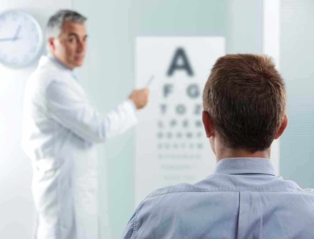Man receiving optometry exam as he looks at a wall chart.