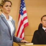 A female witness on a stand with one hand on the Bible and the other raised. Symbolizes God bears witness.