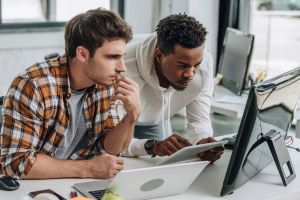 Instructor services illustrated by two male support staff sitting at a computer screen.