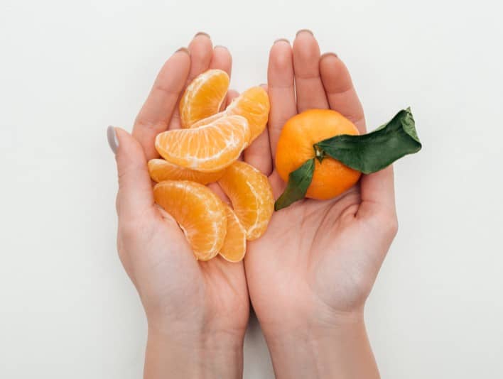 Hands holding pieces of an orange as an example of simplifying a spiritual dream.